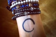 a woman's wrist with several bracelets on it and the letter c written in cursive writing