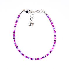 Add a splash of color to your look with this dainty bracelet featuring a playful mix of purple, pink, and white seed beads. Lightweight and stylish, this bracelet is perfect for adding a bit of fun to any outfit. Materials:size 11/0 glass seed beadsbeading wiresilver plated crimp beadssilver plated wire guardssilver plated lobster claw claspsilver plated extension chainsilver plated logo charm