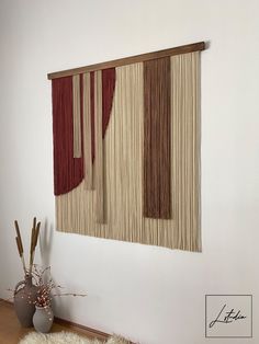 the wall hanging is decorated with red and beige curtains, along with a vase filled with flowers