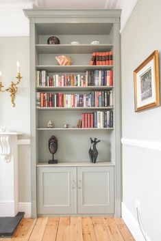 a book shelf with many books on it in a living room next to a fireplace