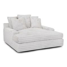 a white couch with four pillows on it's back and one arm facing the camera