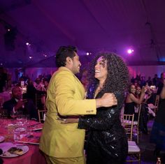 a man and woman dancing together in a room full of tables with purple lights on them