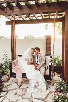 a bride and groom kissing on a swing