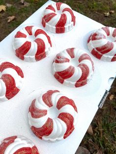 some red and white cupcakes are on a tray with frosted icing