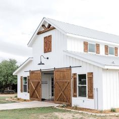 a white barn with wooden doors and windows