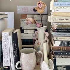 a stack of books and a vase with a flower in it