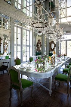 an elegant dining room with chandelier and table set for four people in green chairs