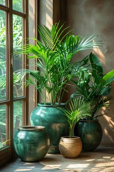 three green vases sitting next to each other in front of a window with plants