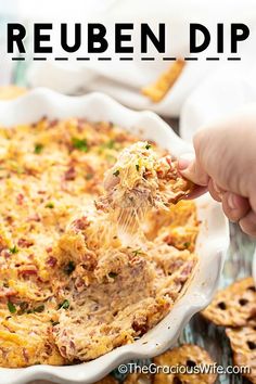 a person scooping some food out of a casserole dish with crackers on the side