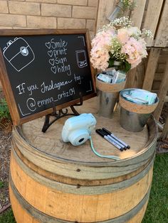 a sign that is on top of a barrel with some flowers in the buckets