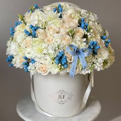 a white hat with blue and white flowers in it on top of a marble table