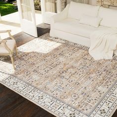 a living room with a white couch and rug on the floor next to a door