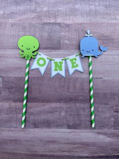 two green and blue straws with paper animals on them