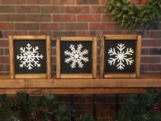 three framed snowflakes are sitting on a mantle