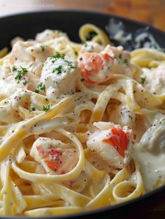 pasta with shrimp and cream sauce in a black bowl on a wooden table top, ready to be eaten