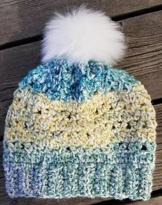 a crocheted hat with a white and blue pom - pom on top