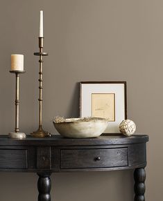 a wooden table with a bowl and two candles on it next to a framed photograph