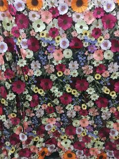 a woman standing in front of a wall with flowers on it