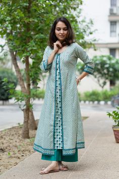 Crafted out of 100% premium cotton, the Mayuri kurta comes as a blessing for those who cannot endure the hassle of a dupatta. The regal silhouette of the kurta comes with modern functional elements like a pair of side pockets. The kurta features exquisite hand-block print which is accentuated with minimal metallic thread work. Pair the kurta with our rama green palazzos for an elegant formal look. Cold Shoulder Blouse Designs, Layered Kurta, Indian Kurti Designs, Kurta Patterns, Kurti Patterns, Simple Kurti Designs, A Line Kurta, Kurtis With Pants