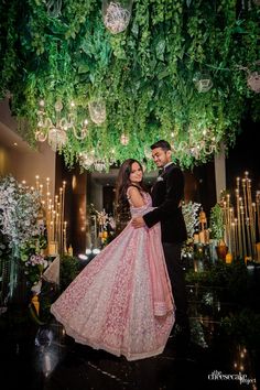 a bride and groom pose for a wedding photo in front of a chandelier