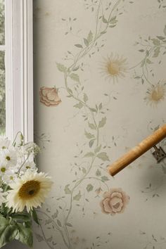 a vase filled with white flowers next to a window sill and wallpapered walls