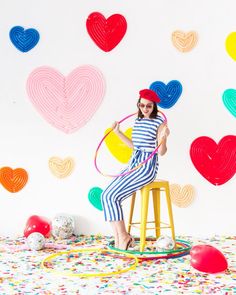 a woman sitting on top of a stool holding a hula hoop in front of hearts