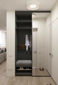 an open closet with clothes hanging on the door and shoes sitting on the floor next to it