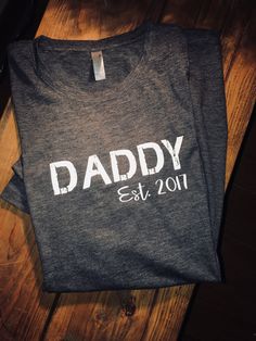 This charcoal tshirt with DADDY in distressed letters and est yr of when he became a dad is simple yet sleek and trendy! Make a great fathers day gift for that special daddy....Modify year no problem just put year in the notes at checkout :) Tshirts are high quality and made up of polyester, cotton and rayon, wash and dry well time after time!! Customizing colors is an option just msg us and we can get it taken care of. Thanks for shopping with us! Dad Fathers Day Gifts, Best Dad Shirt, Papa Shirts, Fathers Day Presents, Presents For Dad, Father's Day T Shirts, Dad Gifts, Worlds Best, Fathers Day Shirts