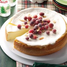 a cake with white frosting and fruit toppings on it sitting on a plate