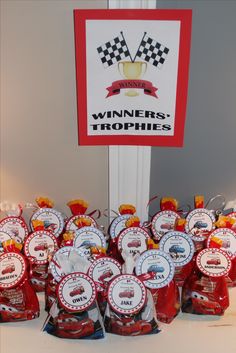 there are many red and white trophies on display in front of a sign that says winners trophies