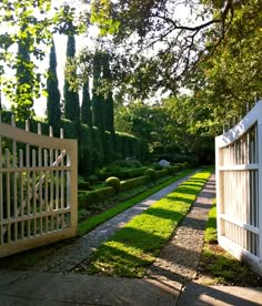 a white gate is in the middle of a garden