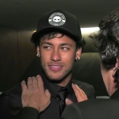 a man wearing a hat and tie is looking into another man's mirror while he adjusts his necktie