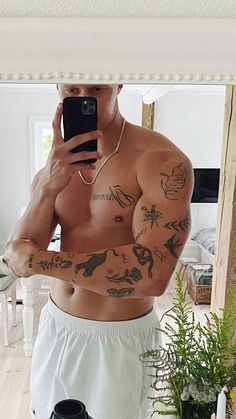 a shirtless man taking a selfie in front of a mirror with his cell phone