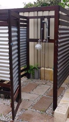 an outdoor shower in the middle of a yard with gravel and rocks on the ground