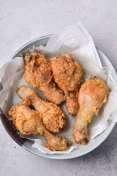 fried chicken wings in a bowl with wax paper on the side and one half eaten