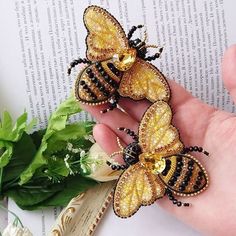 two yellow and black butterfly brooches sitting on top of a book next to flowers