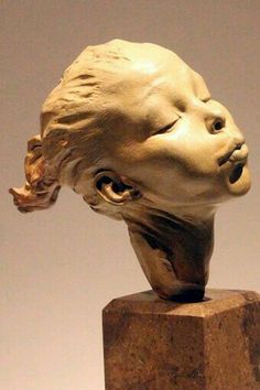 a sculpture of a woman's head on top of a wooden block