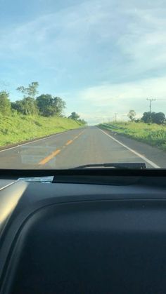 the view from inside a car looking at an empty road and grassy hill in the distance