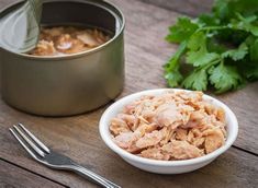 a bowl of food next to a metal container with some parsley on the side