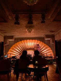 two people sitting at a table in front of a large fan shaped light fixture on the ceiling