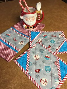 the santa clause is sitting next to some folded napkins and a mug on a table