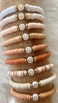 a stack of bracelets that have smiley faces on them, with gold and white beads