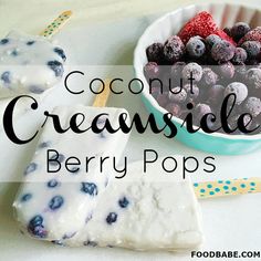 some blueberries and raspberries are in a bowl next to ice cream pops