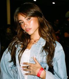 a young woman wearing a jean jacket and holding a cell phone