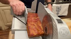 a man is slicing meat into a large piece of meat in an electric food slicer