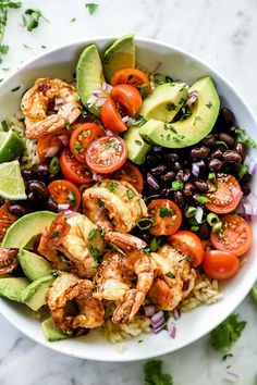 two bowls filled with shrimp, avocado, tomatoes and black beans next to a knife