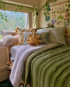 a bed with green comforter and pillows on it in front of a large window