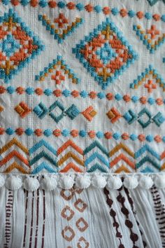 a close up view of an embroidered cloth with tassels and beads on it