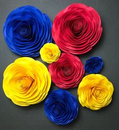 colorful paper flowers arranged in a circle on a gray tablecloth with black background, top view