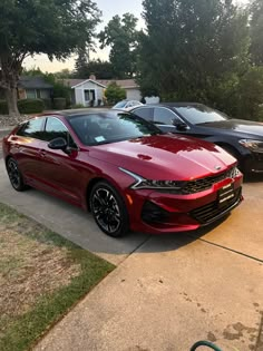 two red cars parked next to each other in a driveway